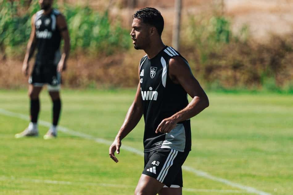 David Sousa em pé no campo com camisa preta do Casa Pia