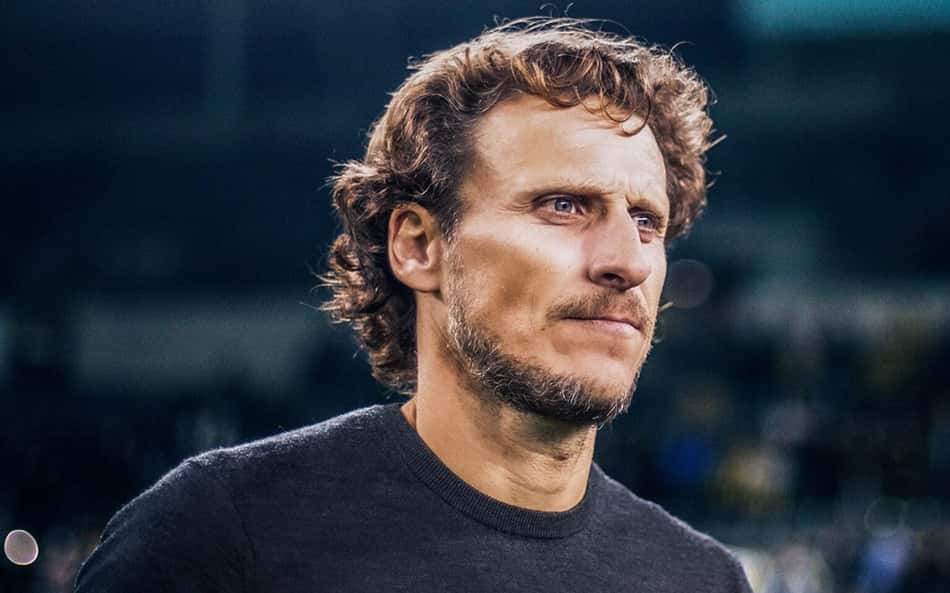 Diego Forlán em anúncio da Seleção Uruguaia, com camisa preta e um letreiro com seu nome e a frase de Bem Vindo em espanhol