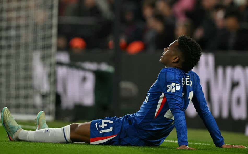 Estêvão caído no gramado após sentir lesão muscular na derrota do Chelsea para o Manchester United, na Premier League