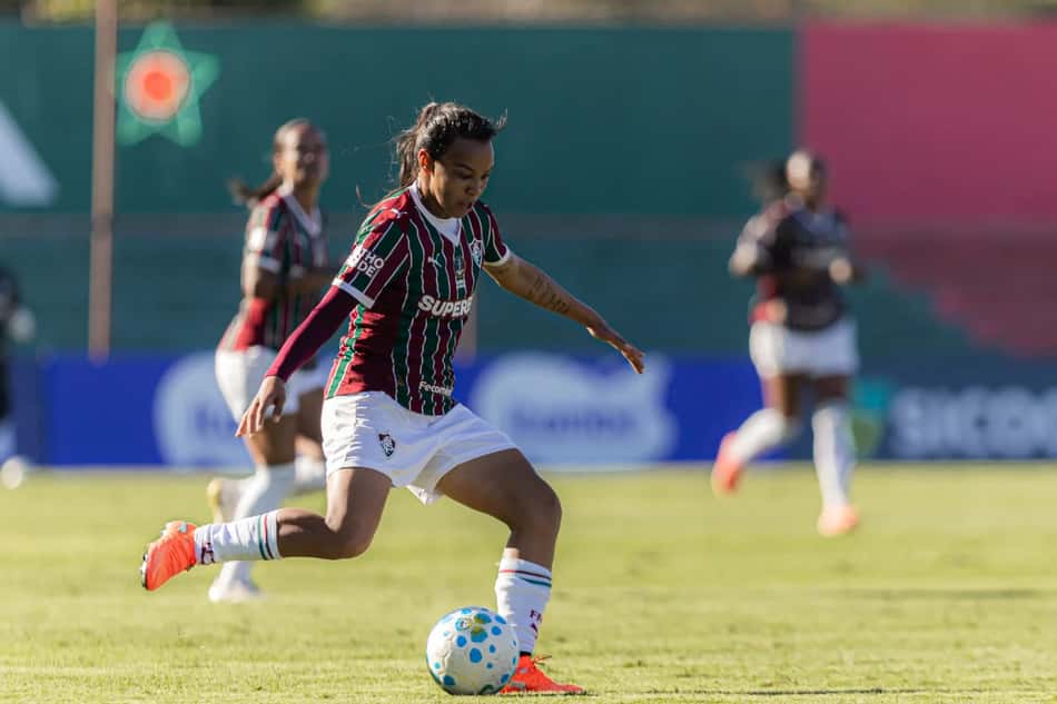 Jogadora do Fluminense em movimento de chutar a bola