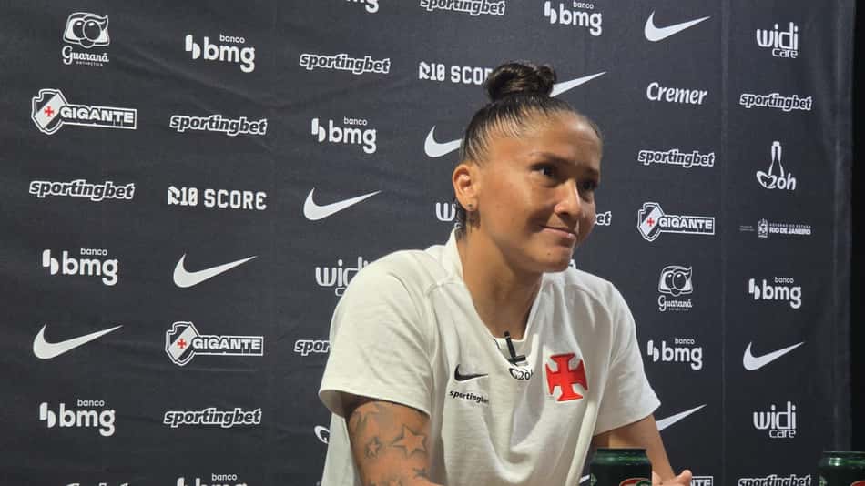 Juh Morais com camisa do VAsco atrás na imagem um Backdrop com patrocinadores do clube