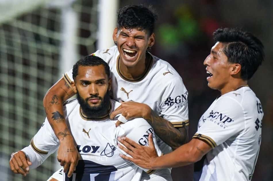 Juninho comemora gol com companheiros de equipe, com um pulando em suas costas