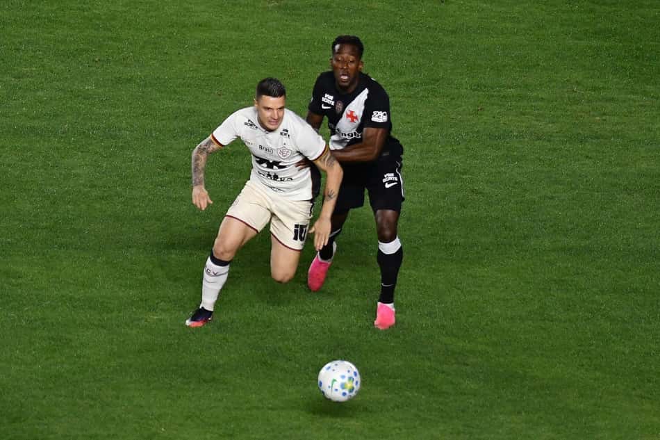 Renato Kayzer, do Vitória, conduzindo a bola com jogador do Vasco atrás