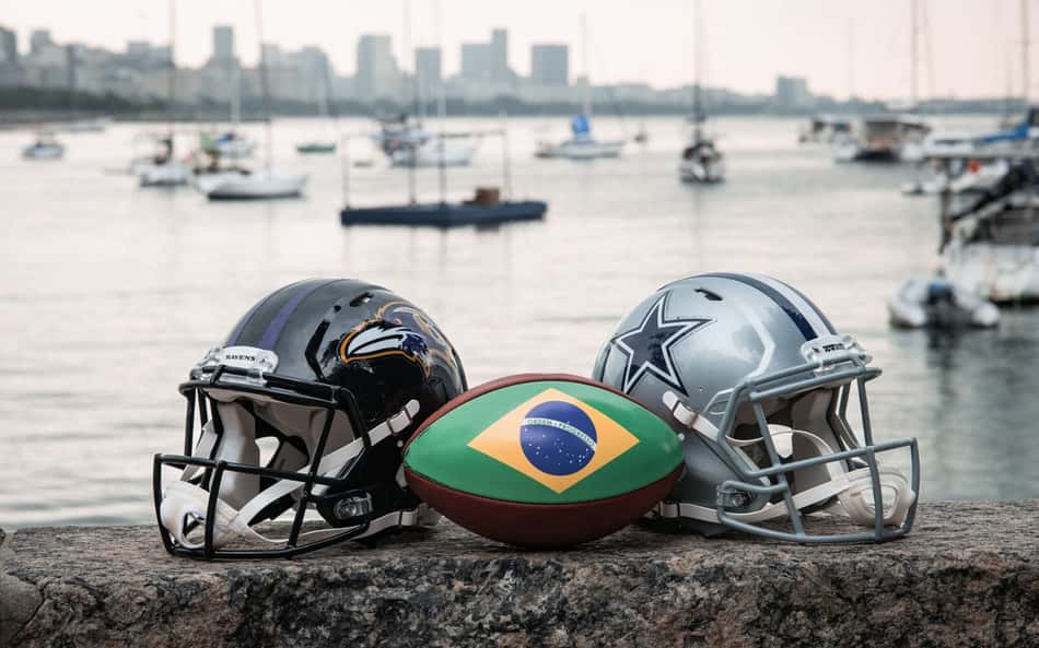 Capacetes de Ravens e Cowboys com bola de futebol americano estampada com a bandeira do Brasil na mureta da Urca, no Rio de Janeiro, palco do jogo da NFL