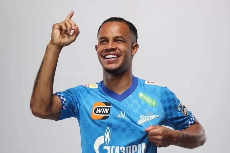 Pedrinho apontando para o alto e segurando o escudo do Zenit com a mão esquerda