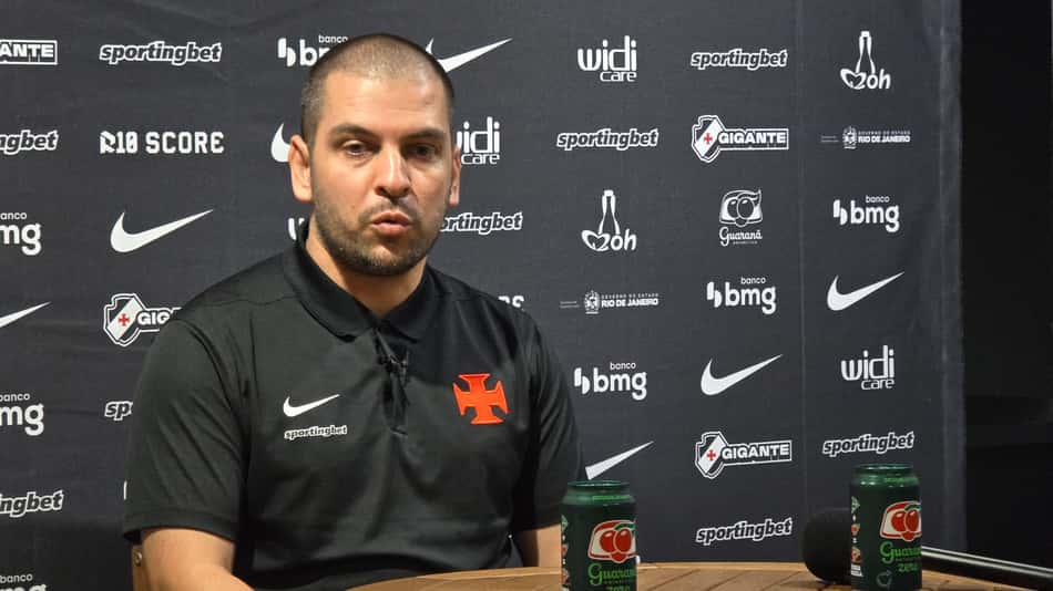 Rubens Franco com camisa do VAsco atrás na imagem um Backdrop com patrocinadores do clube