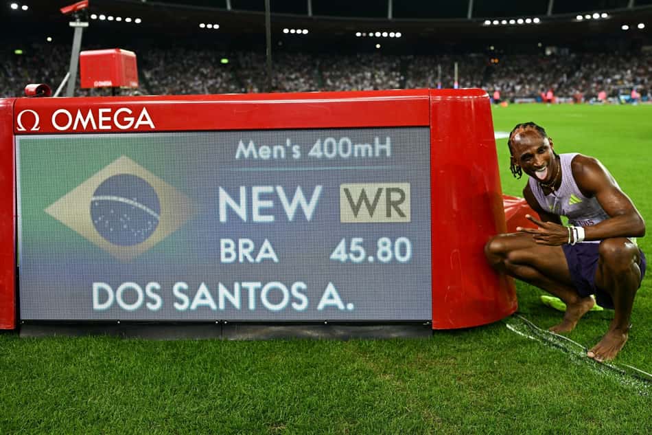 O brasileiro Alison dos Santos posa ao lado de painel mostrando a marca de 45.80 nos 400m com barreiras
