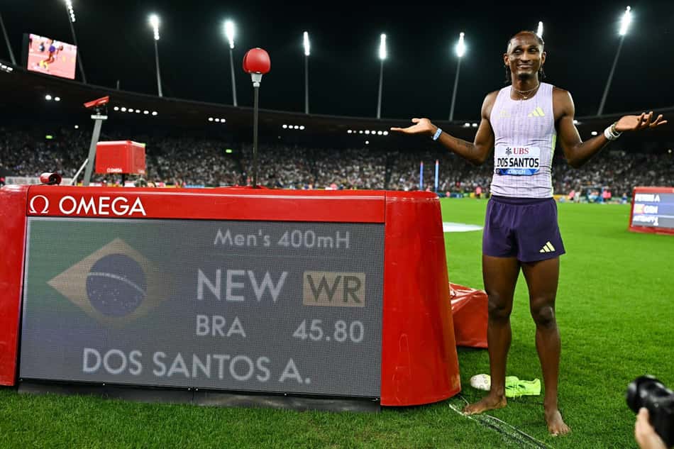 O brasileiro Alison dos Santos posa ao lado de painel mostrando o recorde registrado nos 400m com barreiras