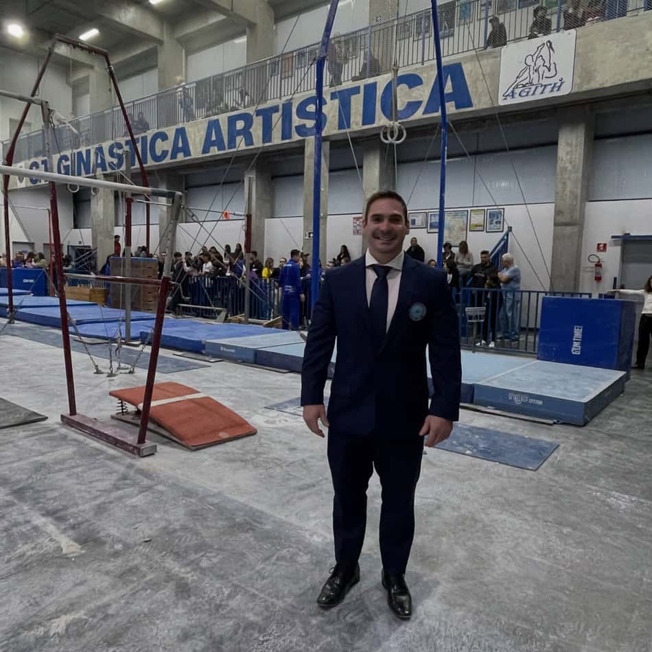 De terno, Arthur Zanetti posa para foto em frente a barras e argolas do ginásio onde foi realizado o Campeonato Paulista de Ginástica Artística