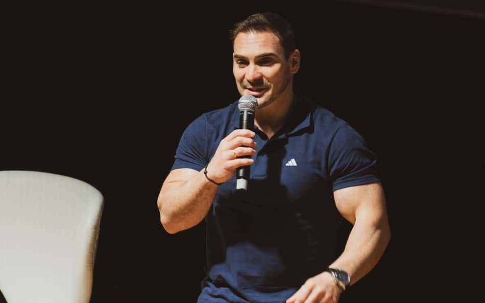 Arthur Zanetti segura microfone com a mão direita e fala durante palestra