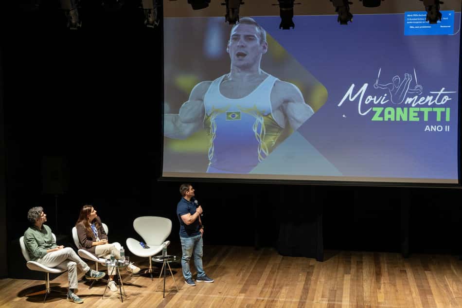 Durante palestra, o ex-ginasta Arthur Zanetti olha para o telão, onde é projetada a imagem do projeto social Movimento Zanetti