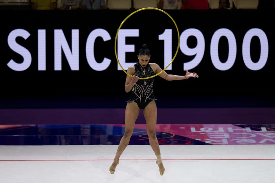 Babi Domingos segura arco com a mão direita e estende o braço esquerdo durante apresentação no Mundial de Ginástica Rítmica