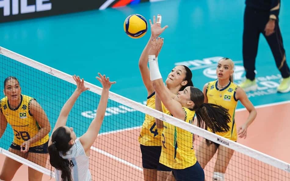 Duas jogadoras do Brasil disputam a bola no meio da rede contra uma atleta da Argentina em jogo do Campeonato Mundial de vôlei feminino sub-17