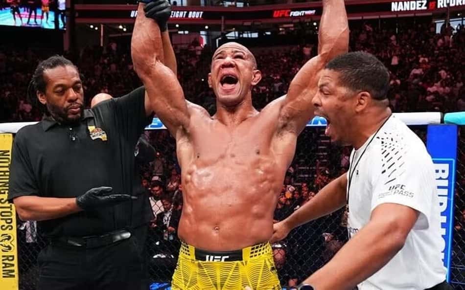 O árbitro Herb Dean levanta o braço direito de Gregory Rodrigues durante o anúncio do brasileiro como vencedor da luta principal do UFC Sacramento