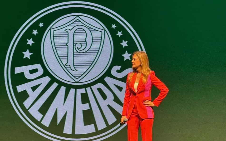 Leila Pereira, presidente do Palmeiras, com o escudo do clube num painel ao fundo