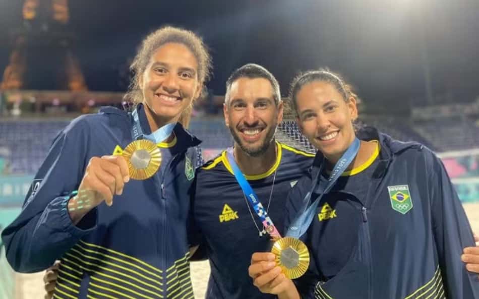 Sorridente, Lucas Palermo posa entre Ana Patrícia e Duda Lisboa após o pódio de vôlei de praia em Paris 2024