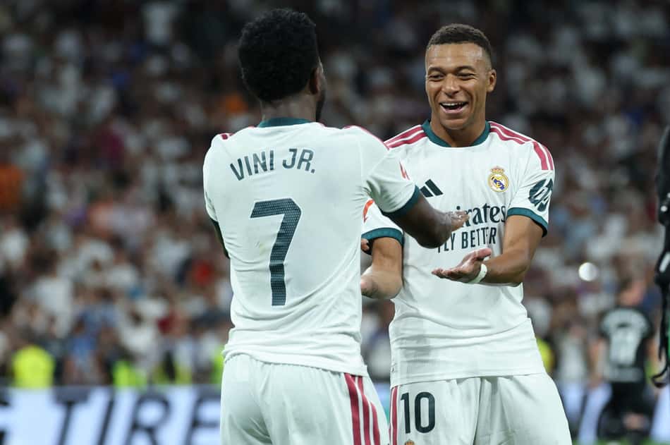 O atacante brasileiro do Real Madrid, número 7, Vinicius Junior (à esquerda), comemora o terceiro gol de sua equipe com o atacante francês do Real Madrid, número 10, Kylian Mbappé, durante a partida do Campeonato Espanhol entre Real Madrid CF e Real Sociedad, no Estádio Santiago Bernabéu, em Madri, em 26 de agosto de 2026