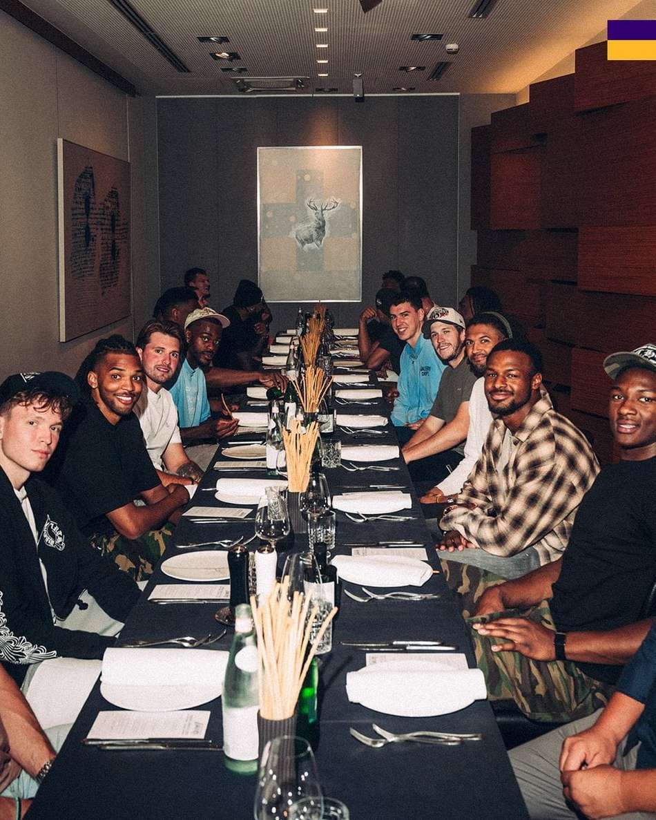 Time dos Los Angeles Lakers se reúne em mesa de jantar com pratos e talheres à frente