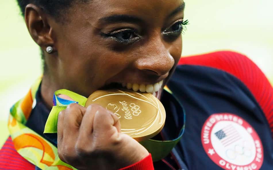 A ginasta Simone Biles morde a medalha de ouro conquistada durante os Jogos Rio 2016