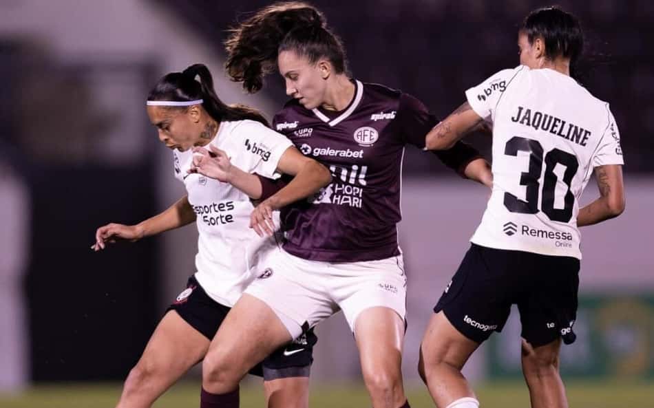 Camila entre duas jogadoras do Corinthians disputando a bola
