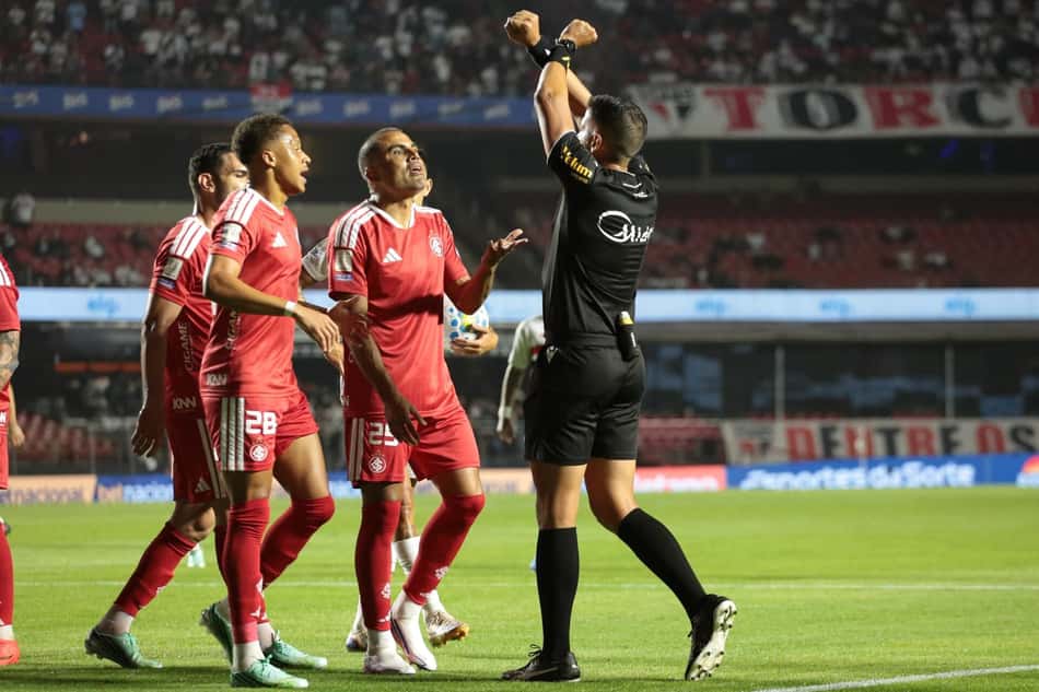 Bruno Arleu de Araújo com s mãos para o alto rodeado de jogadores do Internacional