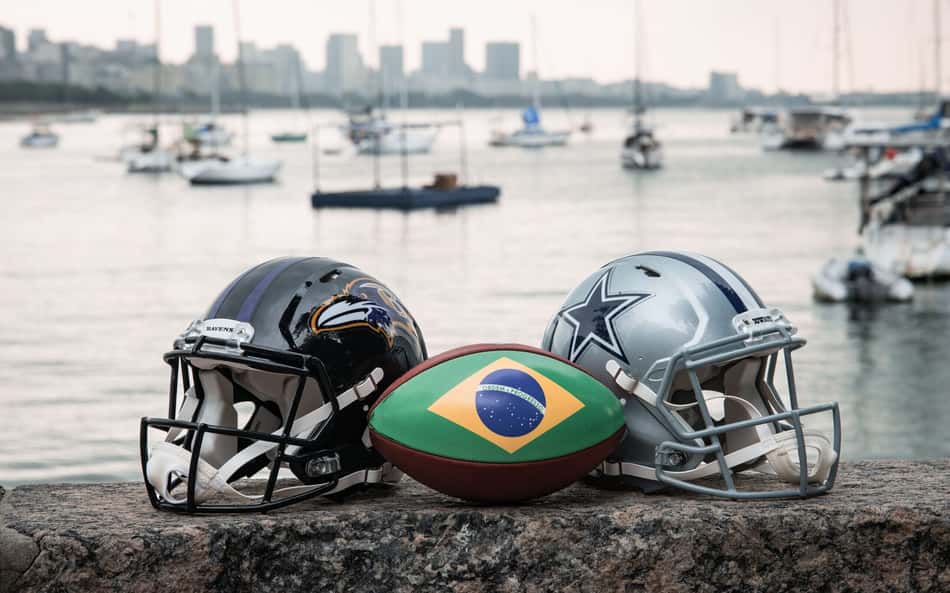 Capacetes de Ravens e Cowboys com bola de futebol americano estampada com a bandeira do Brasil na mureta da Urca, no Rio de Janeiro, palco do jogo da NFL