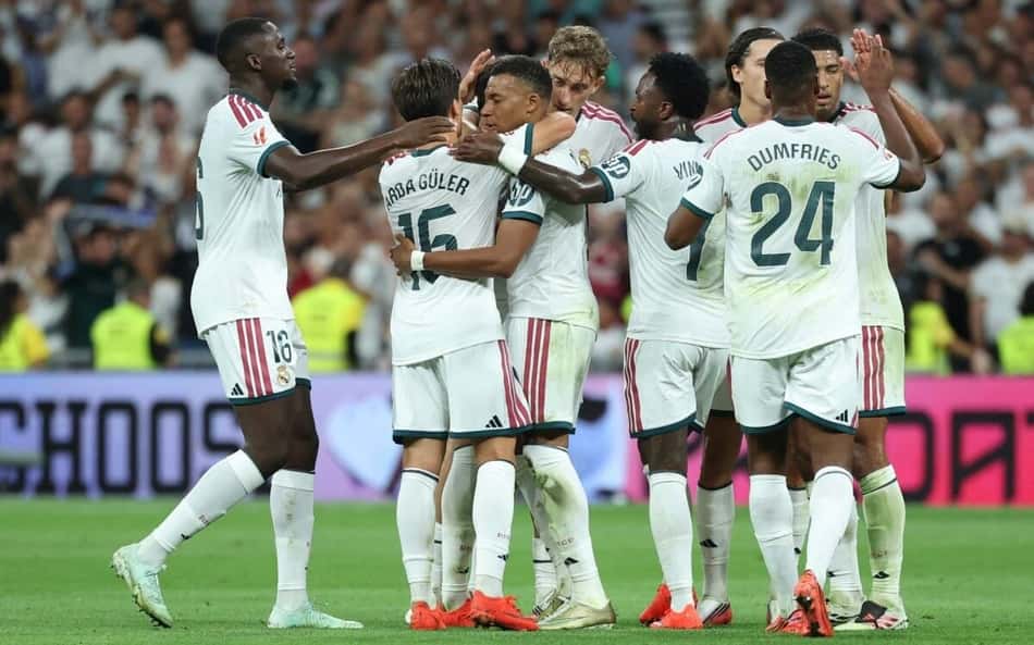 O atacante francês do Real Madrid, camisa 10 Kylian Mbappé (C), comemora com seus companheiros de equipe após marcar o primeiro gol do time durante a partida do Campeonato Espanhol entre Real Madrid CF e Real Sociedad, no Estádio Santiago Bernabéu, em Madri, em 26 de agosto de 2026
