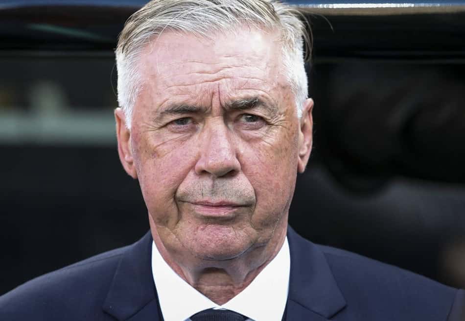 Carlo Ancelotti, de terno, olhando para frente com expressão séria