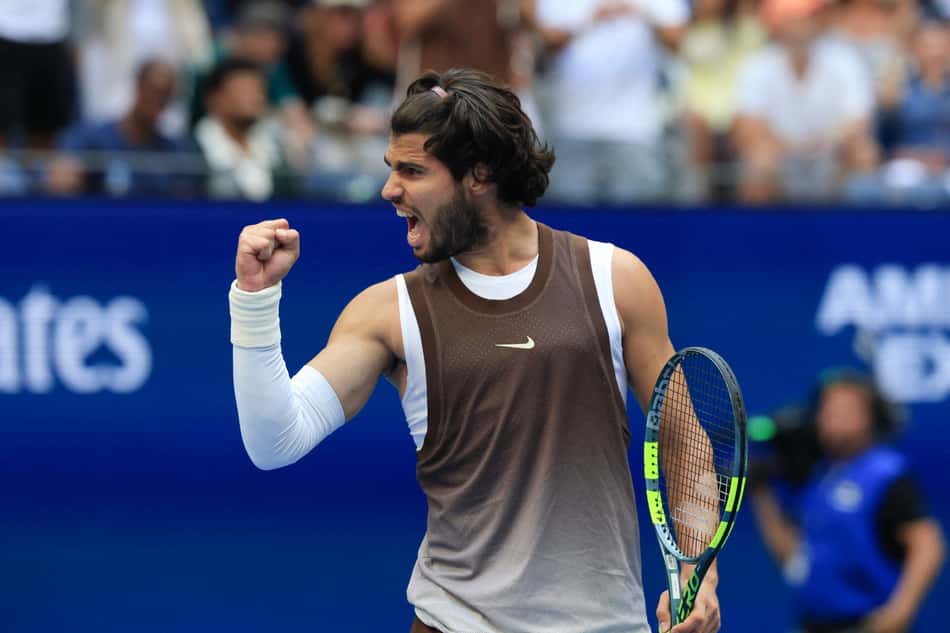 Alcaraz ergue o punho direito e segura a raquete com a mão esquerda enquanto comemora ponto no US Open