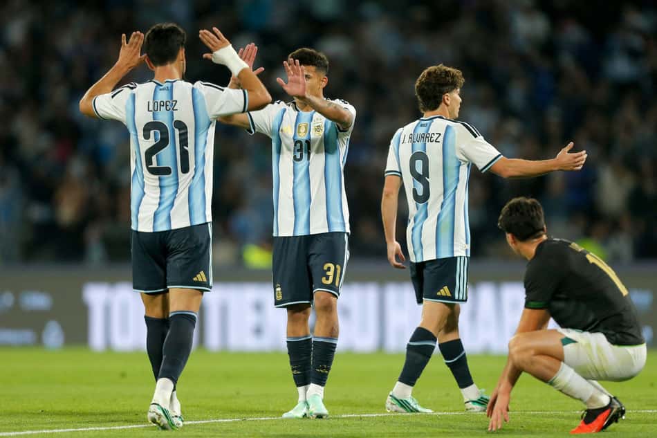 O atacante argentino nº 21 José Manuel López, o atacante nº 31 Leonel Flores e o atacante nº 9 Julián Álvarez comemoram a vitória no amistoso internacional entre Argentina e Bolívia, no Estádio Mario Alberto Kempes, em Córdoba, Argentina, em 30 de setembro de 2026. (Foto: Diego Lima / AFP)