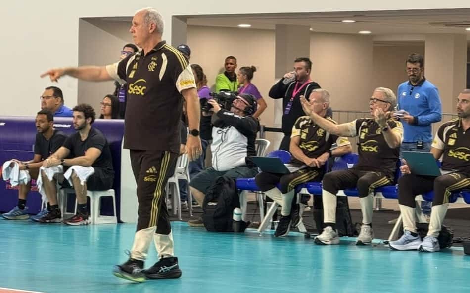 Sentado, Bernardinho gesticula com os braços abertos, enquanto Hélio Griner, em pé, aponta com o dedo indicador direito