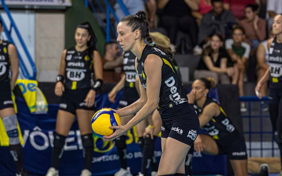 Macris segura bola com as duas mãos enquanto realiza movimento de saque, em jogo do Praia Clube
