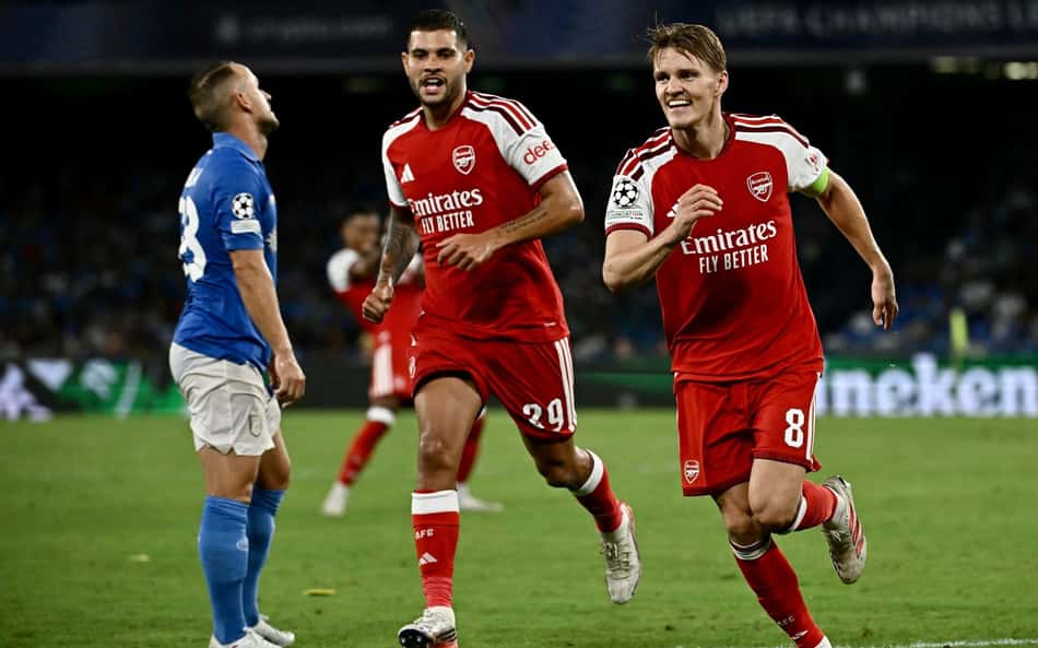 O meio-campista norueguês do Arsenal, número 08, Martin Odegaard (C), comemora com seus companheiros de equipe após marcar o primeiro gol de sua equipe durante a partida da fase de grupos da Liga dos Campeões da UEFA, 1ª rodada, entre Napoli e Arsenal, no Estádio Diego Armando Maradona, em Nápoles, em 9 de setembro de 2026