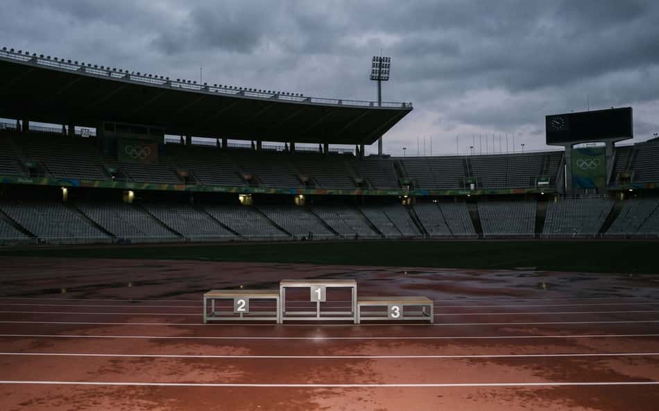Imagem mostra um pódio vazio em uma arena olímpica vazia