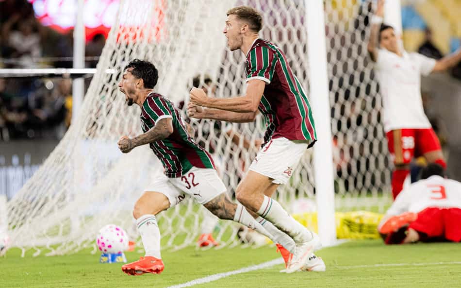 Acosta (Fluminense) comemora gol próximo à baliza, cercado por companheiros.