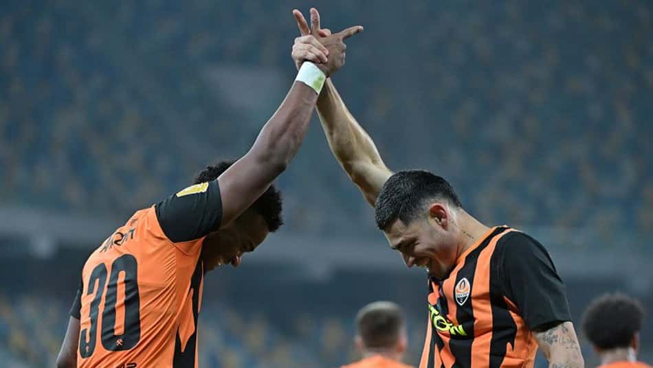 Dois jogadores do Shakhtar Donetsk, vestindo uniforme laranja e preto, celebram com toque de mãos acima da cabeça.