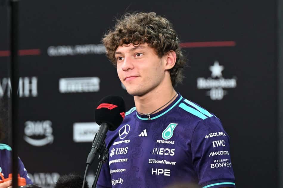 Andrea, piloto de F1, em entrevista, com macacão roxo e logos Petronas/INEOS.s