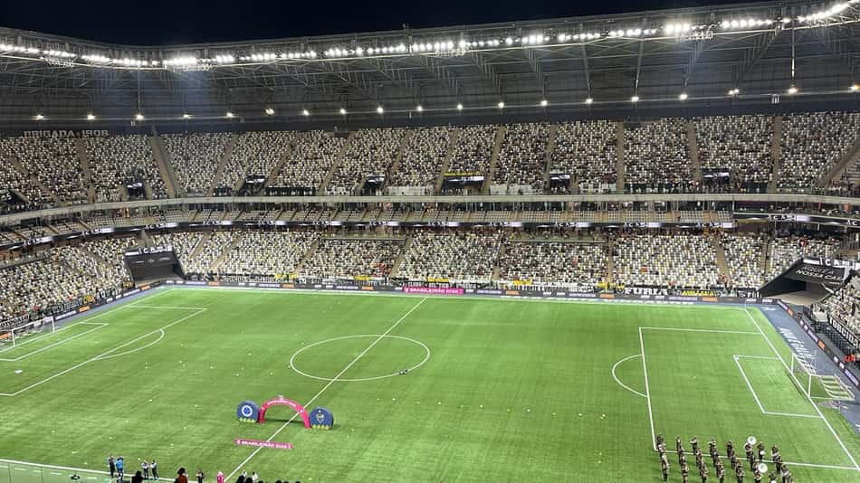 Arena MRV TR: estádio de futebol com arquibancadas cheias e gramado, arco rosa ao centro para cerimônia.