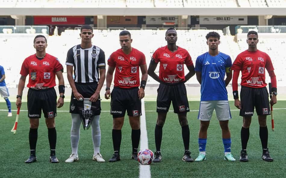 Jogadores alinham-se no gramado: Atlético MG x Cruzeiro Sub 20; bola no centro, estádio vazio ao fundo.