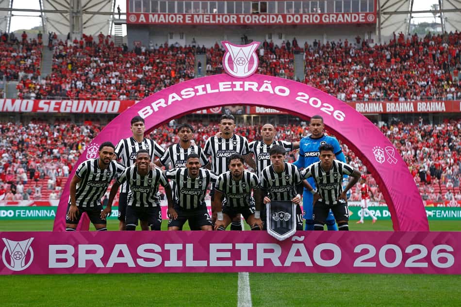 Botafogo em uniforme preto e branco posa sob arco rosa do Brasileirão 2026, com torcida ao fundo