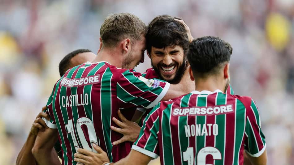 Três jogadores com camisas listradas verde e grená se abraçam em comemoração no campo.