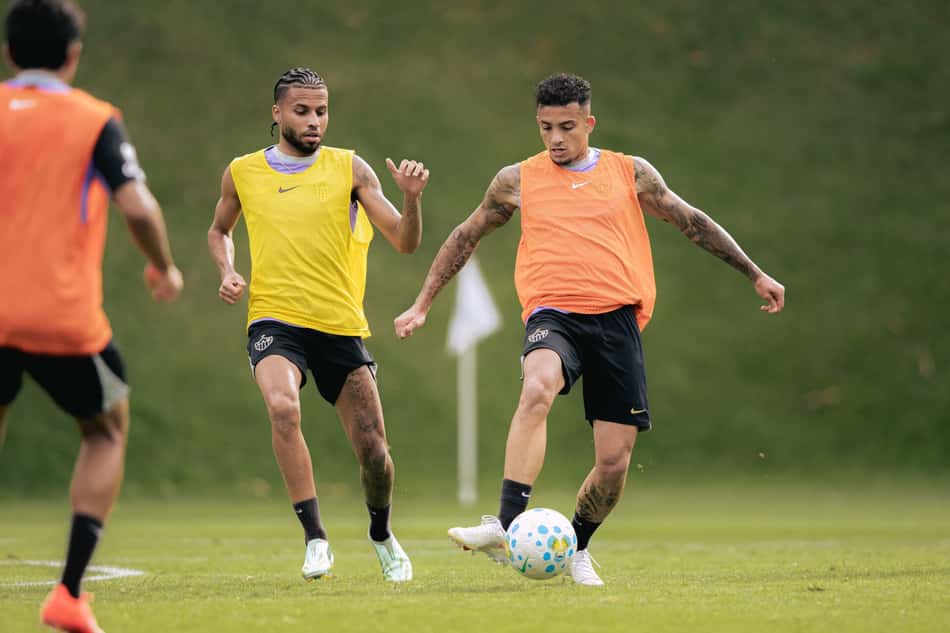 Castaño e Alexsander treinam em campo, um com colete amarelo e outro com colete laranja, com a bola entre eles.