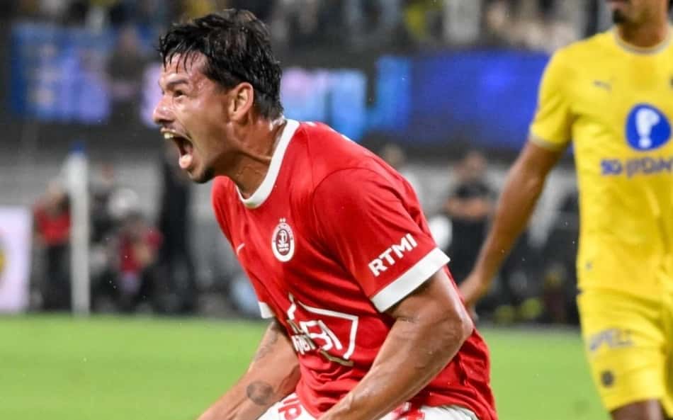 Chico, ex-Sport Israel, celebra durante jogo de futebol pelo time vermelho contra adversário amarelo.