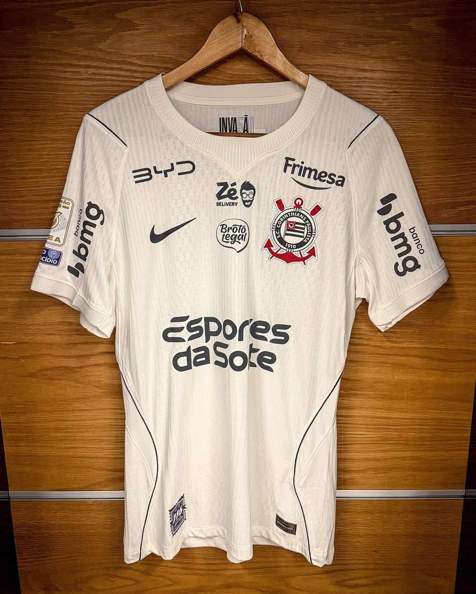 Camisa branca do Corinthians com o emblema do clube, Nike e patrocinadores na frente.