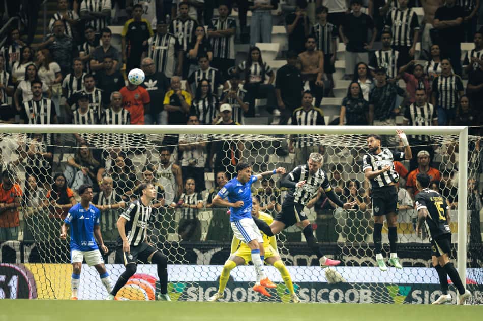 Atlético Mineiro x Cruzeiro em disputa de bola na área, com torcedores ao fundo.