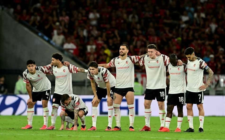 Jogadores do Estudiantes formam linha com braços nos ombros antes de partida, no Maracanã lotado.