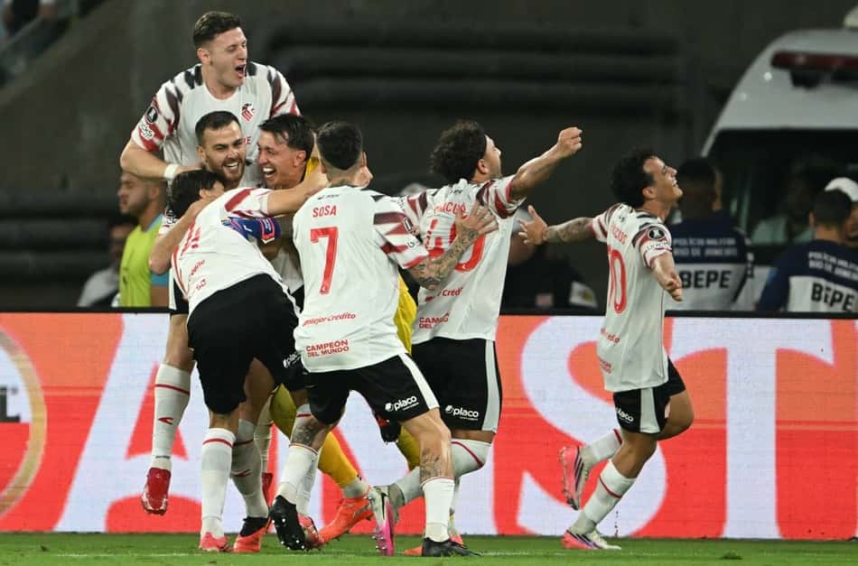 Jogadores do Estudiantes de La Plata celebram a vitória, abraçados no campo.