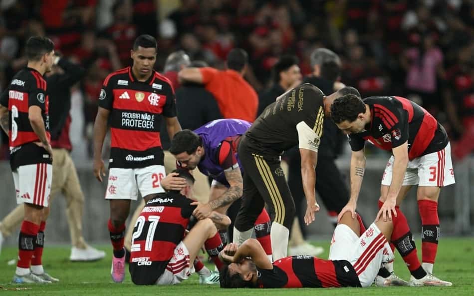Jogadores do Flamengo cercam e consolam companheiro caído no gramado após eliminação, durante a partida.