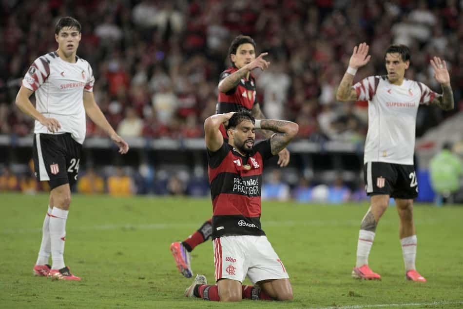 Jogador do Flamengo ajoelhado em campo durante Flamengo x Estudiantes; outros jogadores ao redor durante a partida.