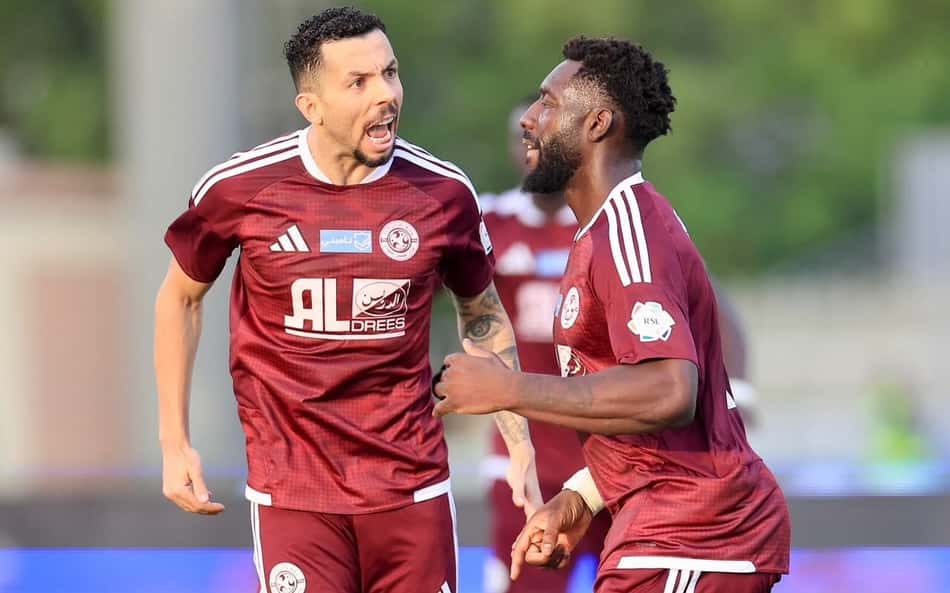 Dois jogadores do Al Faisaly comemoram durante treino no campo.